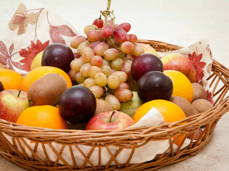 Ein Korb mit verschiedenem Obst wie Weintrauben, Äpfeln und Orangen Ein Korb mit verschiedenem Obst wie Weintrauben, Äpfeln und Orangen