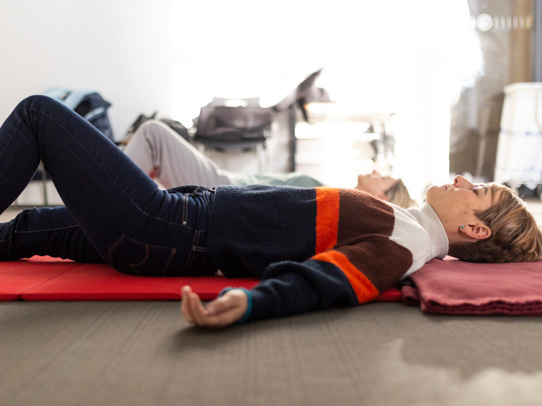 Frauen liegen mit geschlossenen Augen auf Matte und praktizieren achtsames Yoga Frauen liegen mit geschlossenen Augen auf Matte und praktizieren achtsames Yoga