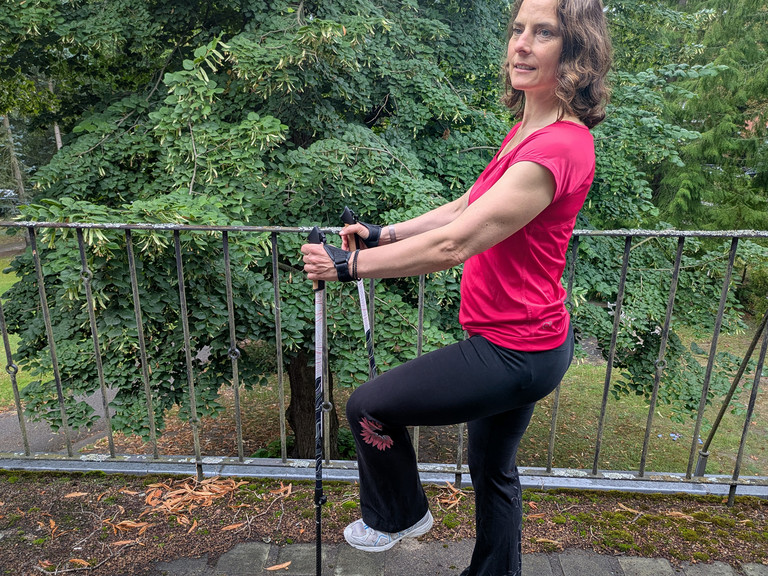 Therapeutin bei einer Nordic Walking Übung mit Stöckern auf einer Terrasse Therapeutin bei einer Nordic Walking Übung mit Stöckern auf einer Terrasse